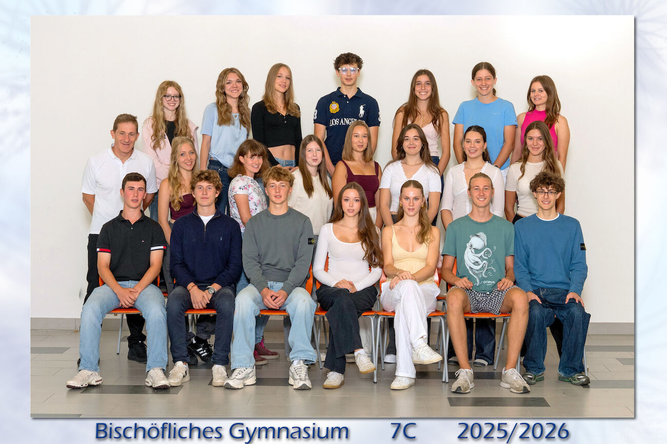 Eine Gruppe von Schülern und ein Lehrer posieren für ein Klassenfoto in drei Reihen.