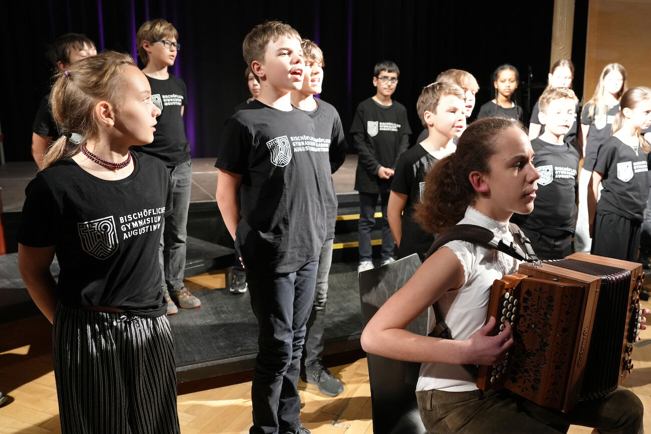 Ein Chor von Kindern und Jugendlichen singt in einer Kirche unter der Leitung eines Dirigenten.