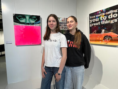 Zwei junge Frauen stehen in einer Galerie vor farbenfroher moderner Kunst.