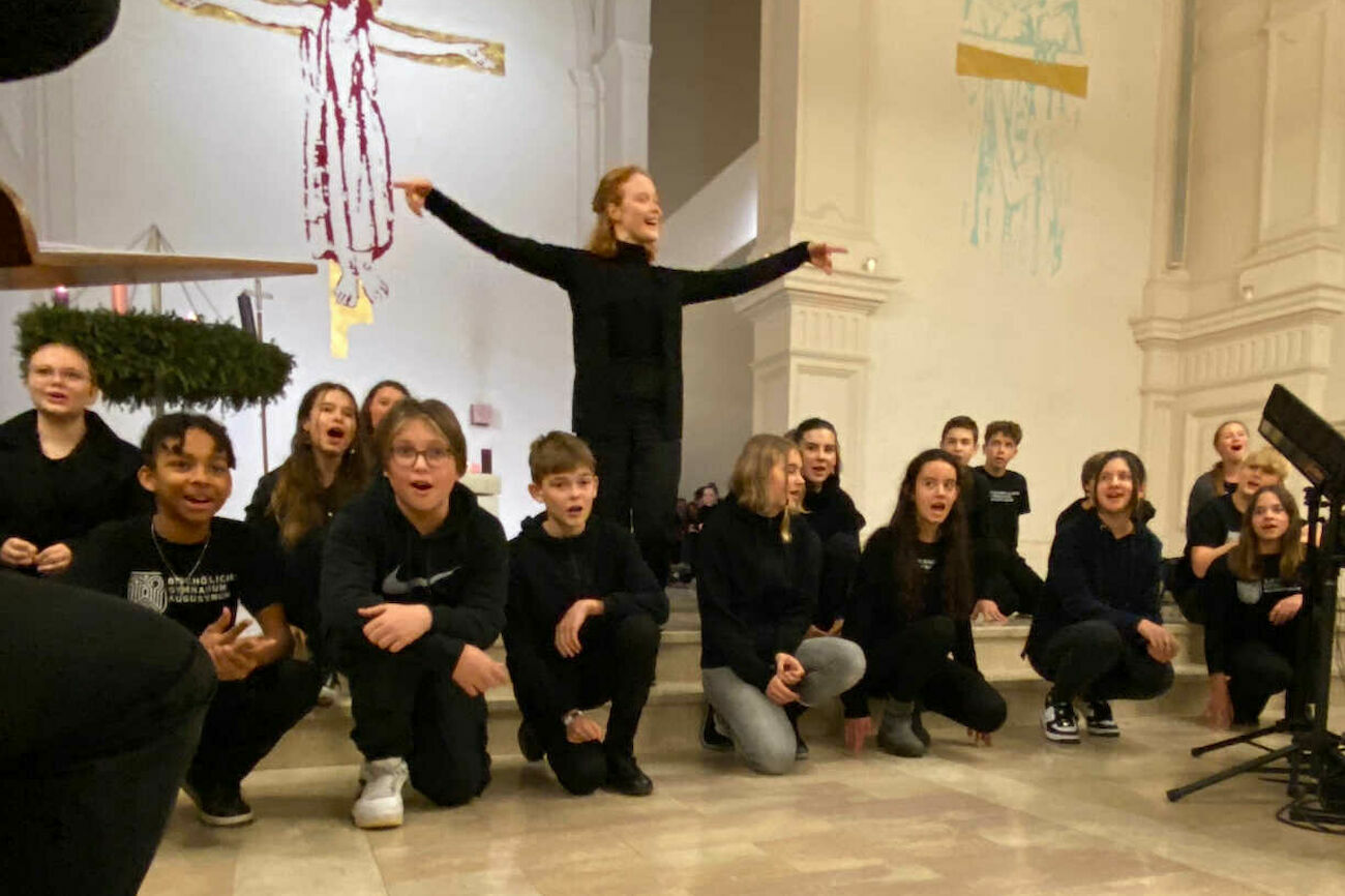 Schwarz gekleidete Kinder treten begeistert auf einer Bühne in einer Kirche auf.